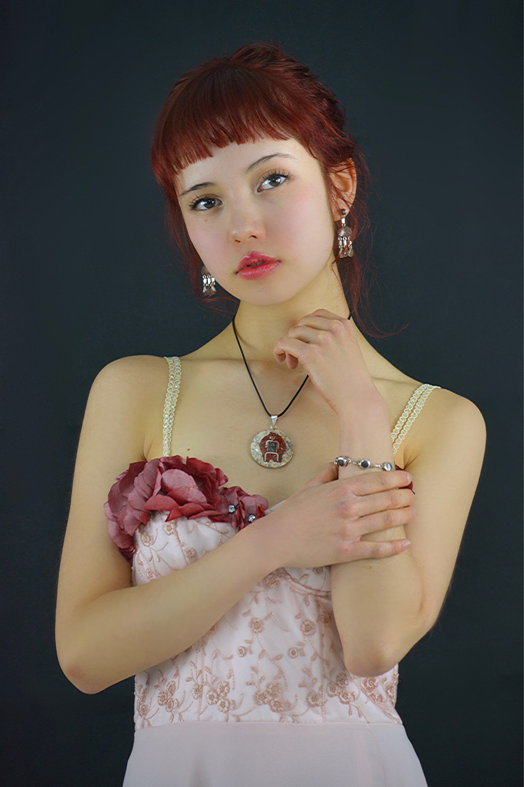 joven modelo pelirroja con collar sosteniendo una de sus muñecas donde tiene un brazalete